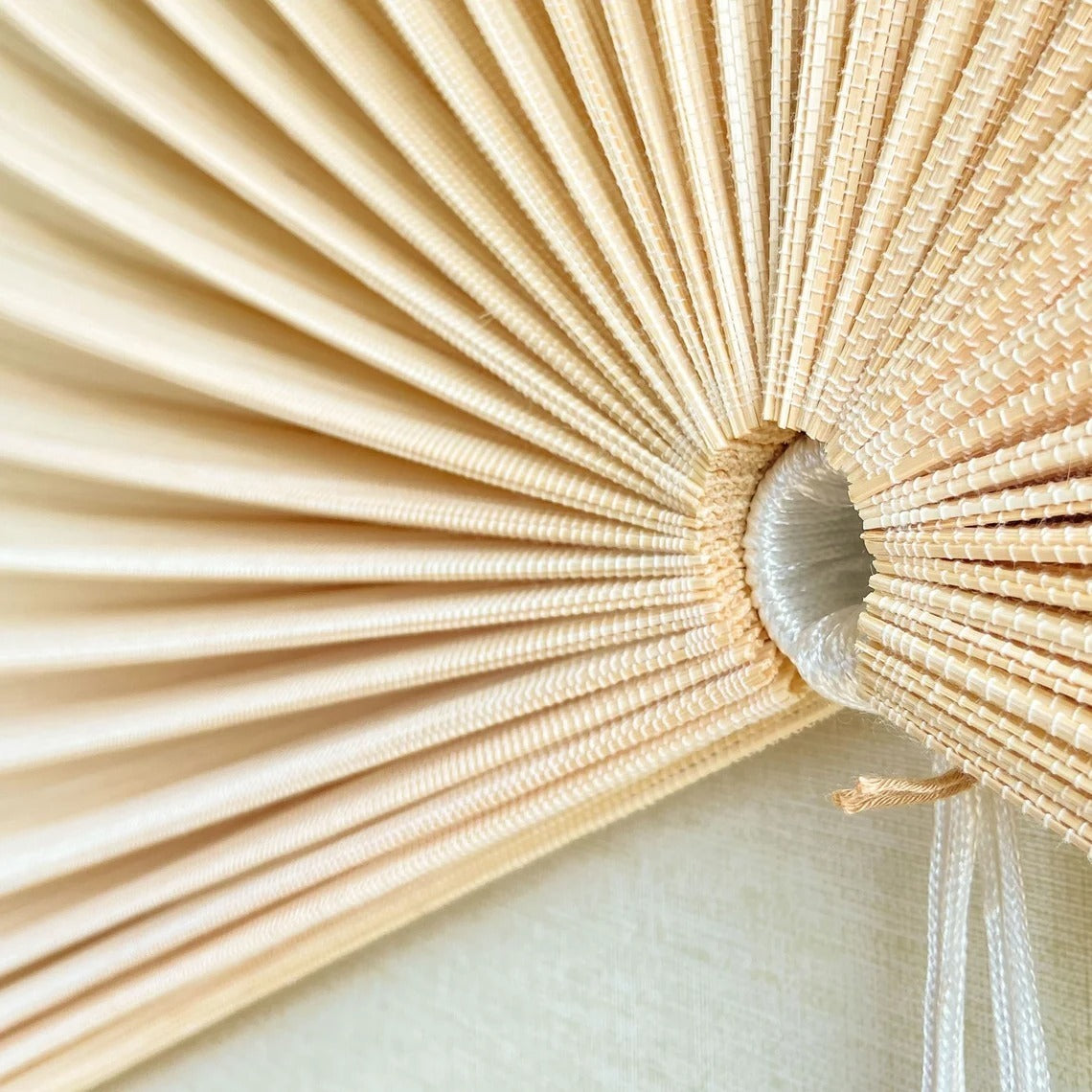 Close-up of the natural bamboo frame and woven pleats at the centre of an ERISO hanging wall fan