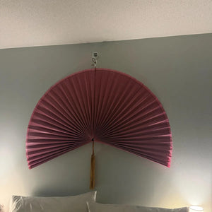Customer photo: Magenta hanging wall fan above a bed on a sage wall