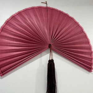 Customer photo: close-up of a Magenta pleated bamboo wall fan with dark tassel