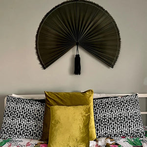 Customer photo: Moss Green hanging wall fan above a bed with patterned and velvet cushions