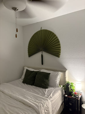 Customer photo: Moss Green hanging wall fan above a white bed with green cushions